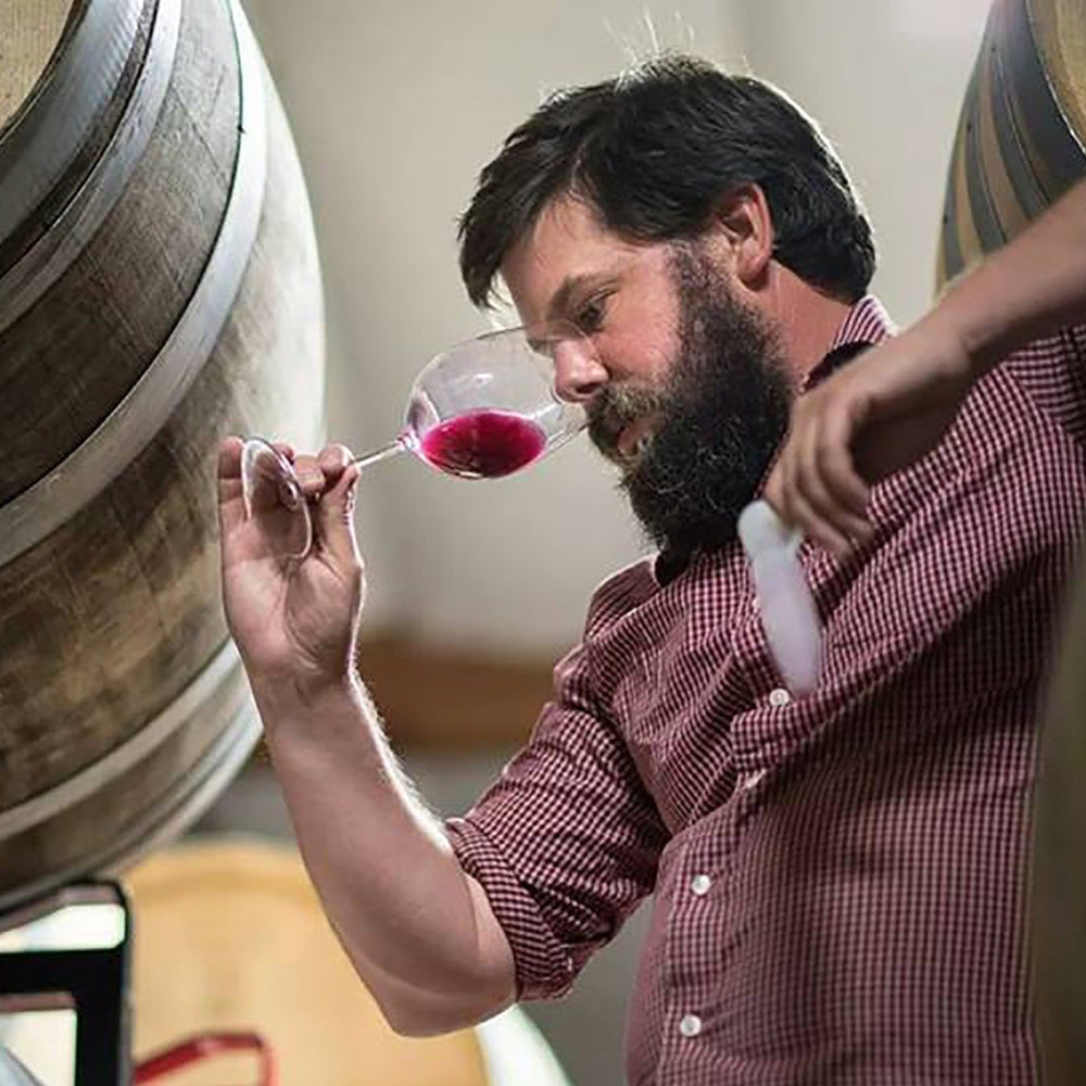 John Lockwood in the cellar with a glass of wine