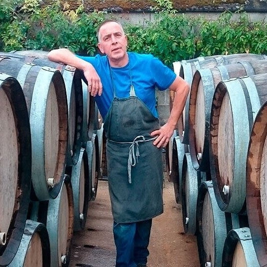Fabrice Gass standing with the wine barrels