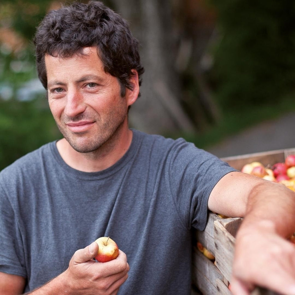 Jacques Perritaz next to bins of apples